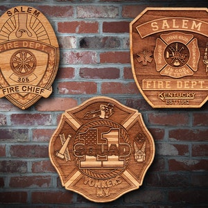 May include: Three wooden plaques with engraved fire department logos. The top left plaque is a shield with the words "Salem Fire Dept" and "Fire Chief" and the number "305". The top right plaque is a shield with the words "Salem Fire Dept", "Kentucky Est. 1952", and "Isaiah 43:29" with a cross and the words "Honor", "Courage", and "In God We Trust". The bottom plaque is a cross with the words "Squad 1" and "Yonkers NY".