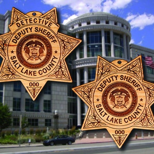May include: Two wooden star-shaped ornaments with the text "DETECTIVE DEPUTY SHERIFF SALT LAKE COUNTY 000" on each. The ornaments are brown and have a detailed design.