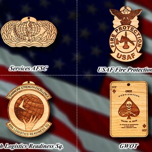 May include: Four wooden ornaments featuring different designs. The top left ornament is a brown and tan wood cutout of a military insignia with a globe, lightning bolt, and laurel wreath. The top right ornament is a brown and tan wood cutout of a military insignia with a fire extinguisher, axe, and the text "FIRE PROTECTION USAF". The bottom left ornament is a brown and tan wood cutout of a military insignia with a globe, hand, and the text "TEAMWORK STRENGTH EXCELLENCE 90th LOGISTICS READINESS SQ". The bottom right ornament is a brown and tan wood cutout of a playing card with a skull and crossbones, and the text "GWOT GUNFIGHTERS DEALERS OF DEATH OIF OEF".
