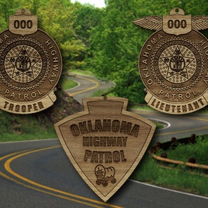 Könnte beinhalten: Drei Holzornamente mit dem Logo der Oklahoma Highway Patrol. Die beiden oberen Ornamente sind rund und zeigen das Staatssiegel von Oklahoma. Das untere Ornament hat die Form eines Schildes mit der Aufschrift "Oklahoma Highway Patrol".
