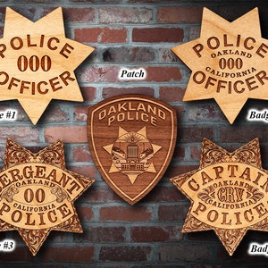 May include: Four wooden police badges with different ranks, including Officer, Sergeant, and Captain. The badges are all in the shape of a six-pointed star and feature the words "Oakland Police" and "California".