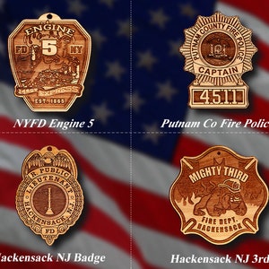 May include: Four wooden ornaments featuring different designs. The first ornament is a brown and gold shield with the text "Engine 5 FD NY 14th St Express Est. 1865". The second ornament is a brown and gold star with the text "Putnam County Fire Police Captain 4511". The third ornament is a brown and gold shield with the text "R. Public Lieutenant Hackensack N.J. FD". The fourth ornament is a brown and gold shield with the text "Mighty Third Fire Dept. Hackensack".