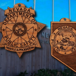 May include: Two wooden ornaments featuring the Nevada Department of Public Safety logo. The first ornament is a star-shaped badge with the text "Nevada Department of Public Safety Parole & Probation". The second ornament is a state outline of Nevada with the text "Nevada Public Safety Call for our Country".