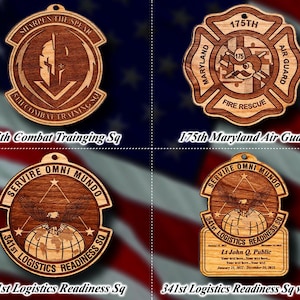 May include: Four wooden ornaments with various designs and text. One features a shield with a warrior, another a fire rescue emblem, and two with an eagle and globe. Text includes "5th Combat Training Sq", "175th Maryland Air Guard", and "341st Logistics Readiness Sq".