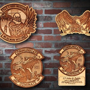 May include: Four wooden plaques with intricate laser-cut designs. One features an eagle with a banner reading "ALL GAVE SOME, SOME GAVE ALL." Another depicts a helicopter and text "WE DO MORE WITH LESS." The other two have a dinosaur and the words "COMMUNICATE" and "DOMINATE."