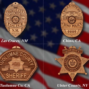 May include: Four wooden ornaments shaped like police badges. The top left ornament is a Las Cruces, NM police badge. The top right ornament is a Chino, CA police badge. The bottom left ornament is a Tuolumne County, CA sheriff's badge. The bottom right ornament is an Ulster County, NY sheriff's badge.