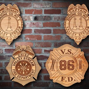 May include: Four wooden firefighter badges with different designs. The top left badge says "Lieutenant Engine Co. No. 2 Valley Stream F.D.". The top right badge says "Captain Engine Co. No. 2 Valley Stream F.D.". The bottom left badge says "Chief Valley Stream Fire Department". The bottom right badge says "V.S. 86 F.D.".