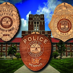 May include: Three wooden police officer badges with the University of Tennessee logo and the words "Police Officer" and "University of Tennessee" on them. The badges are in front of a brick building with a clock tower.