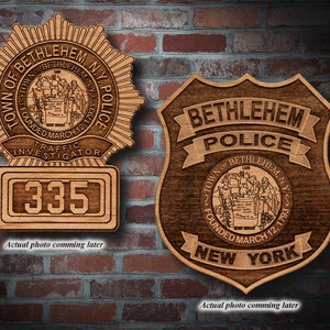 May include: Two wooden plaques with a police badge design. The left plaque has a starburst design with the text "Town of Bethlehem, N.Y. Police" and "Founded March 12, 1793". The right plaque has a shield design with the text "Bethlehem Police" and "Town of Bethlehem, N.Y. Founded March 12, 1793 New York".