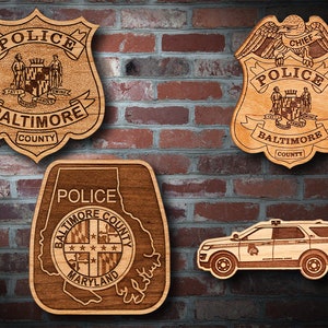 May include: Four wooden plaques with laser-engraved designs of the Baltimore County Police Department. The plaques feature the department's logo, a police car, and the words "Police", "Baltimore County", and "Maryland".