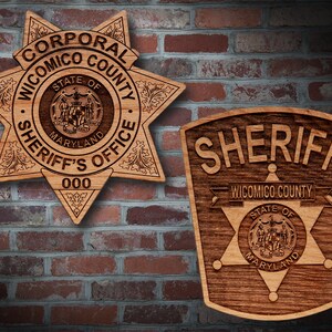 May include: Two wooden sheriff's badges, one with a six-pointed star and the text "CORPORAL WICOMICO COUNTY SHERIFF'S OFFICE STATE OF MARYLAND 000", and the other with the text "SHERIFF WICOMICO COUNTY STATE OF MARYLAND".