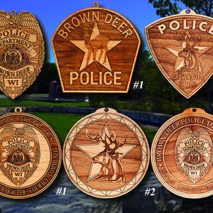 May include: Six wooden ornaments featuring a deer and the words "Brown Deer Police Department" with different designs. The ornaments are all brown and have a star shape.