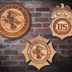 May include: Three wooden plaques with the Department of Justice seal. The top plaque features the words "Department of Justice" and "Qui Pro Domina Justitia Sequitur" with a bald eagle. The middle plaque features the words "Department of Justice" and "Drug Enforcement Administration" with a bald eagle and the letters "US" in the center. The bottom plaque features the words "Department of Justice" and "Federal Bureau of Prisons" with a bald eagle.