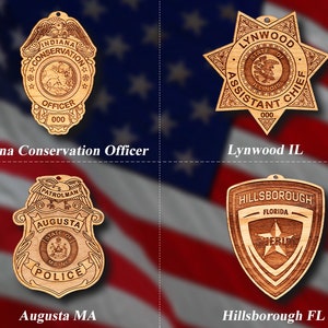 Könnte beinhalten: Vier Holzornamente in Form von Abzeichen, jedes mit einem anderen Design und Text. Das Ornament oben links ist ein braunes Abzeichen mit dem Text "INDIANA CONSERVATION OFFICER 000". Das Ornament oben rechts ist ein braunes sternförmiges Abzeichen mit dem Text "LYNWOOD STATE OF ILLINOIS ASSISTANT CHIEF 000". Das Ornament unten links ist ein braunes Abzeichen mit dem Text "PATROLMAN AUGUSTA STATE OF MAINE POLICE". Das Ornament unten rechts ist ein braunes schildförmiges Abzeichen mit dem Text "HILLSBOROUGH FLORIDA SHERIFF".