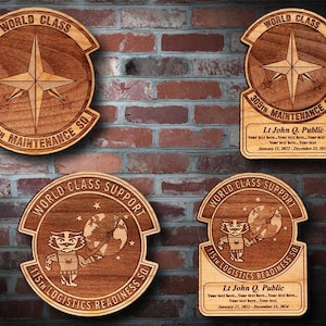 May include: Four wooden plaques with a star and text "World Class" and the unit's name and number. The plaques are decorated with a star and a compass rose. The text on the plaques includes "305th Maintenance SQ", "115th Logistics Readiness SQ", and "Lt John Q. Public".