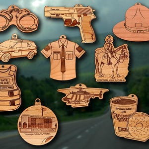 May include: A collection of wooden ornaments featuring law enforcement themes. Includes a police car, handcuffs, a gun, a uniform, a hat, a helicopter, a horse-riding officer, a coffee cup with a donut, a bulletproof vest, and a building.