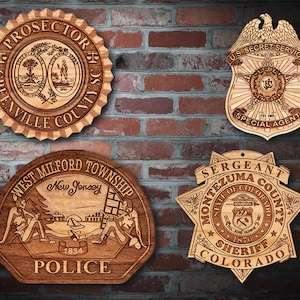 Könnte beinhalten: Vier Holzschilder mit aufwendigen Designs. Eines lautet "PROSECUTOR GREENVILLE COUNTY", ein anderes "U.S. SECRET SERVICE SPECIAL AGENT", ein drittes "WEST MILFORD TOWNSHIP POLICE" und das letzte "SERGEANT MONTEZUMA COUNTY SHERIFF COLORADO".
