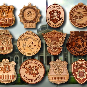 May include: Twelve wooden ornaments featuring different Nassau County Police Department badges. The badges are engraved with various titles, including "Police Officer", "Detective", "Sergeant", "Emergency Service Unit", "Motor Officer", "Aviation", "Mounted Unit", and "Police Medic".