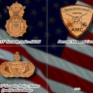 Könnte beinhalten: Vier Holzornamente mit militärischen Abzeichen. Das Ornament oben links ist ein braunes Schild mit einem blauen Adler und dem Text "SECURITY POLICE DEPARTMENT OF THE AIR FORCE A1234". Das Ornament oben rechts ist ein braunes Schild mit dem Text "PARSONS MOUNTED CAVALRY John Doe AMC". Das Ornament unten links ist ein braunes Schild mit einem Globus, einem Adler und einem Lorbeerkranz. Das Ornament unten rechts ist ein verschwommenes Bild einer amerikanischen Flagge.