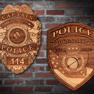 May include: Two wooden police badges, one with the words "Captain" and "Police" and the number "114", and the other with the words "Police", "Broken Arrow", "Est." and "1903".