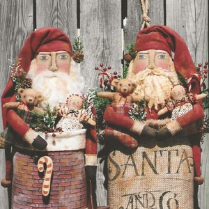 May include: Two handmade Santa Claus dolls, one in a red suit holding a sack that says "Santa and Co. Toys & Gifts" and the other in a red suit holding a brick chimney with a candy cane.