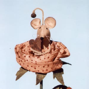 May include: A felt mouse with a heart in its paws sits inside a pink and white polka dot felt rose. The rose is on a green stem with a ladybug on a leaf. A sign reads "A flower for thee with &hearts; from me".