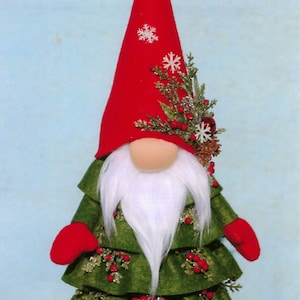 May include: A green Christmas tree gnome with a red hat, white beard, and red berry accents. The gnome is wearing a green dress with a red trim and has a red hat with white snowflakes.