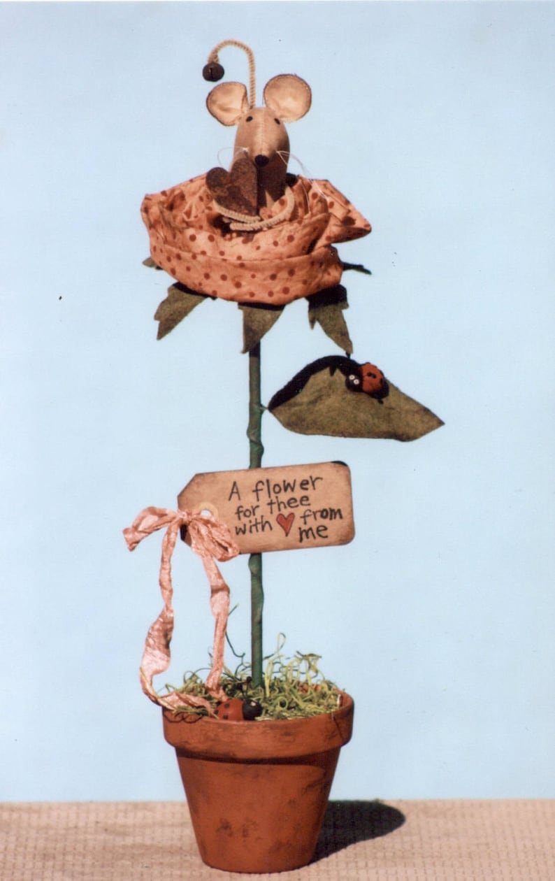 May include: A handmade felt mouse sits in a pink and white polka dot rose. The rose is on a green stem with a brown pot and a sign that reads "A flower for thee with love from me".