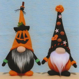Peut inclure: Deux décorations de gnome d'Halloween. L'un a un chapeau orange en forme de citrouille avec un visage noir et une araignée sur le dessus. L'autre a un chapeau noir avec des citrouilles et des étoiles oranges. Les deux ont des barbes blanches et des corps oranges.