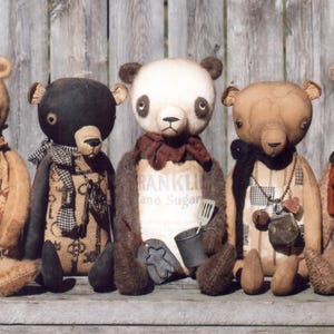 May include: Five handmade plush toys, each with a unique personality and design. The toys are made of fabric and have embroidered details. The toys are sitting on a wooden surface.