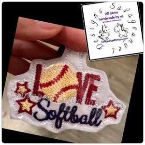 May include: White iron-on patch with red and gold embroidery. The patch says "Love Softball" with a gold baseball in the middle and two gold stars on either side.