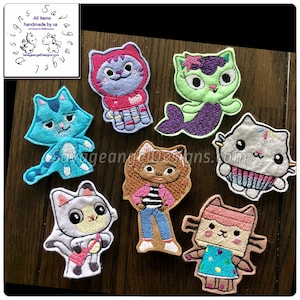 May include: Seven felt appliques of various cartoon characters. The characters include a mermaid cat, a girl with brown hair and a pink jacket, a cat wearing a red and white striped shirt, a cat wearing a blue shirt, a cat wearing a pink shirt, a cat wearing a white shirt, and a cat wearing a blue shirt.