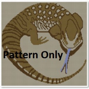 May include: A cross-stitch pattern of a brown and black lizard with a blue tongue, curled in a circle. The pattern is on a beige background.