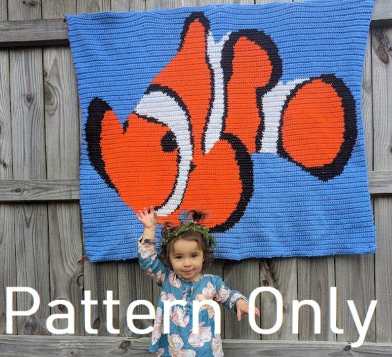 May include: A crochet pattern for a colorful clownfish blanket. The pattern is shown on a blue background with a white border. The pattern is for sale, but the blanket is not included.