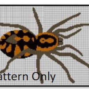 Könnte beinhalten: Ein Kreuzstichmuster einer braunen und orangefarbenen Spinne mit schwarzen Markierungen. Die Spinne hat acht Beine und blickt auf den Betrachter. Das Muster ist auf einem grauen Hintergrund.