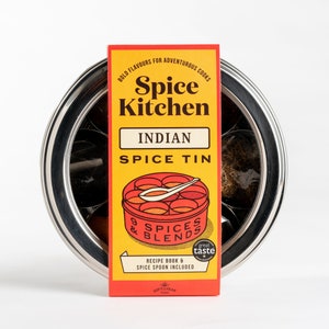 Puede incluir: Una lata de especias de metal amarilla y roja con el texto "Spice Kitchen" y "Indian Spice Tin". La lata tiene una tapa roja con una cuchara y 9 compartimentos para especias. El texto "9 Spices & Blends" está en la tapa. La lata está etiquetada como "Great Taste" e incluye un libro de recetas y una cuchara para especias.