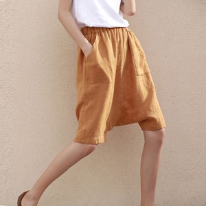 May include: A pair of loose-fitting, brown linen shorts with pockets. The shorts have a wide waistband and a relaxed fit.