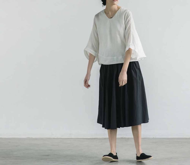 May include: A white linen top with a scoop neck and 3/4 sleeves paired with a black midi skirt.