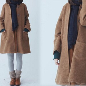 May include: A long-sleeved brown coat with a dark blue scarf and a single button fastening.