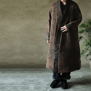 May include: A long brown coat with a black trim and a collar. The coat is made of a soft, textured fabric and has a relaxed fit.