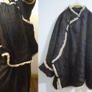 Puede incluir: Un abrigo marrón oscuro con ribete y forro color crema. El abrigo tiene un diseño único con cuello mandarín y cierres de palanca. La tela tiene un aspecto texturizado, y el abrigo parece cálido y adecuado para el clima frío.