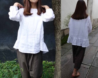 May include: A white linen blouse with a ruffled hem and long sleeves. The blouse is loose-fitting and has a relaxed, casual style.