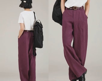 May include: A pair of wide-leg pants in a deep burgundy color. The pants have a high waist and are made of a linen-like fabric. The pants are shown on a model wearing a white t-shirt and a brown belt.