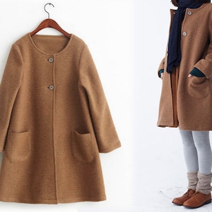 May include: A brown, long-sleeved, button-up coat with a round neckline and two pockets. The coat is made of a soft, textured fabric.