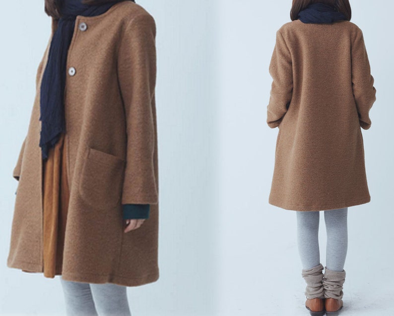May include: A long-sleeved brown coat with a collar and pockets. The coat is worn over a grey shirt and grey trousers.
