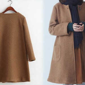 May include: A brown long-sleeved coat with a simple design and a slightly flared hem. The coat has a button closure and two pockets.