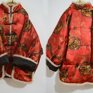 May include: A red silk jacket with a gold and black floral pattern. The jacket has a mandarin collar, a button closure, and a white fur lining. The sleeves have a black lining and a white fur cuff.