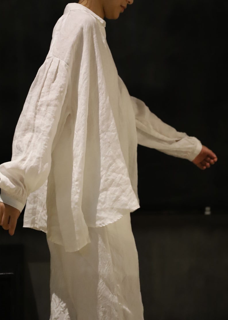 Pu&ograve; includere: Una camicia bianca di lino a maniche lunghe e vestibilit&agrave; rilassata. La camicia ha un aspetto leggermente drappeggiato sulle spalle e una lunghezza leggermente pi&ugrave; lunga sul retro.