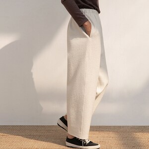 May include: A pair of wide-leg, cream-colored pants with a straight leg and a slightly cropped length. The pants have a simple design and are made of a soft, comfortable fabric.