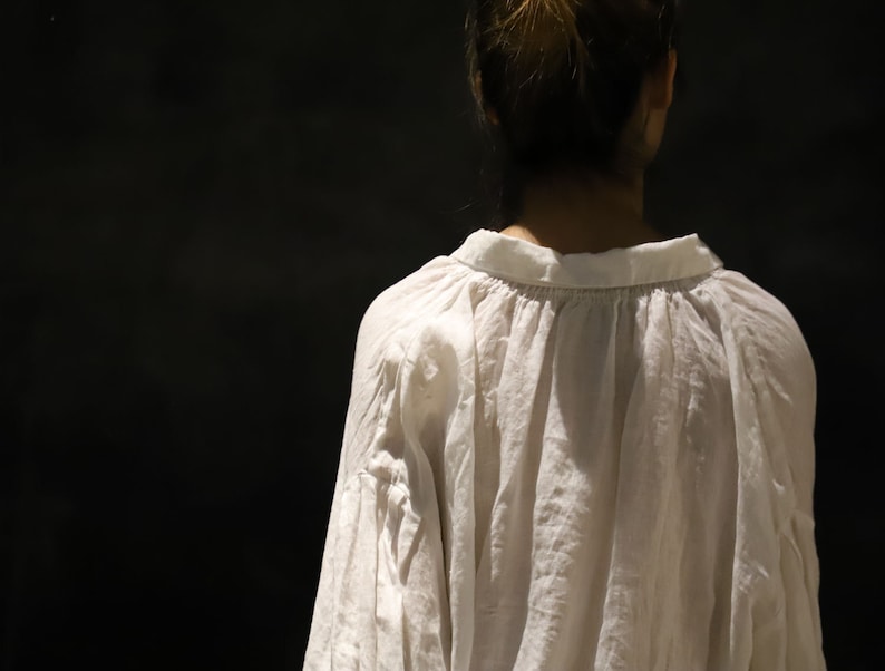 Pu&ograve; includere: Una blusa bianca ampia con scollo arricciato e maniche lunghe. La blusa &egrave; realizzata in un tessuto leggero e ha una vestibilit&agrave; rilassata.